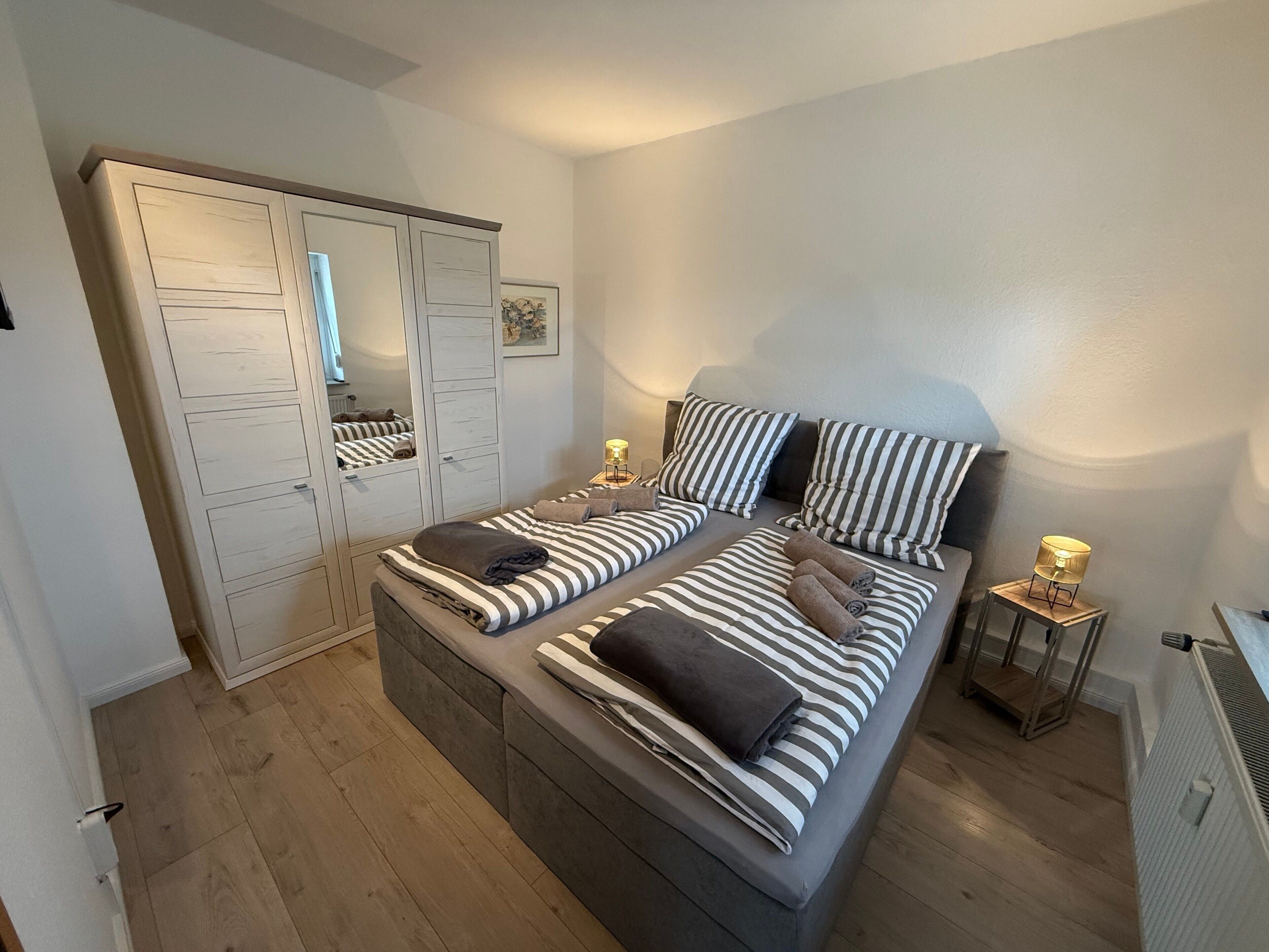 Ein Schlafzimmer mit Bett, Nachttischen, einem Kleiderschrank und einem Heizkörper.