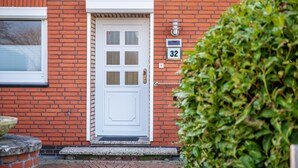 Un bâtiment en briques rouges avec une porte blanche, une boîte aux lettres et le numéro « 32 » peint sur le mur.