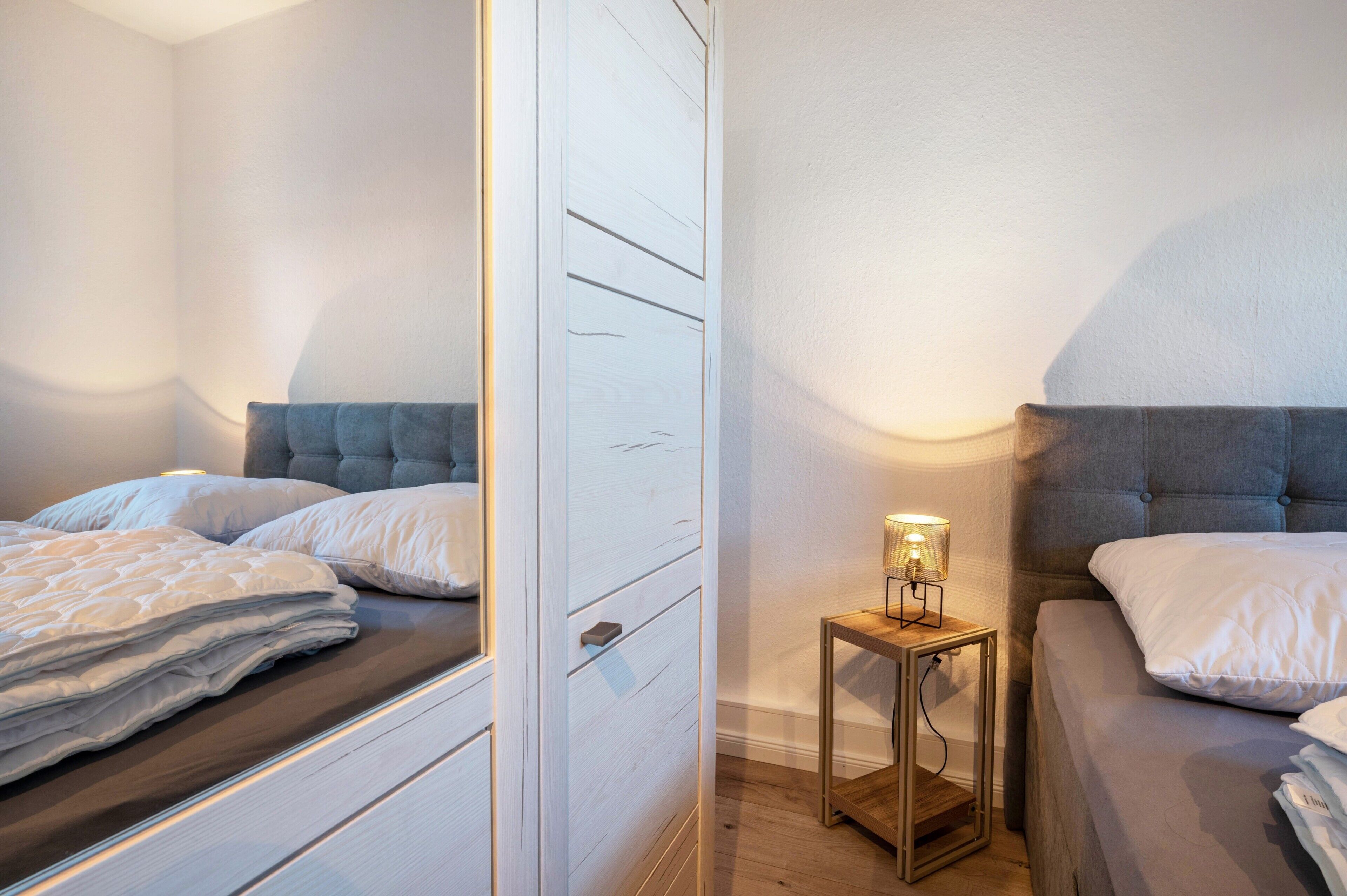 Ein Schlafzimmer mit zwei Betten, einem Nachttisch mit Lampe und einem Kleiderschrank.