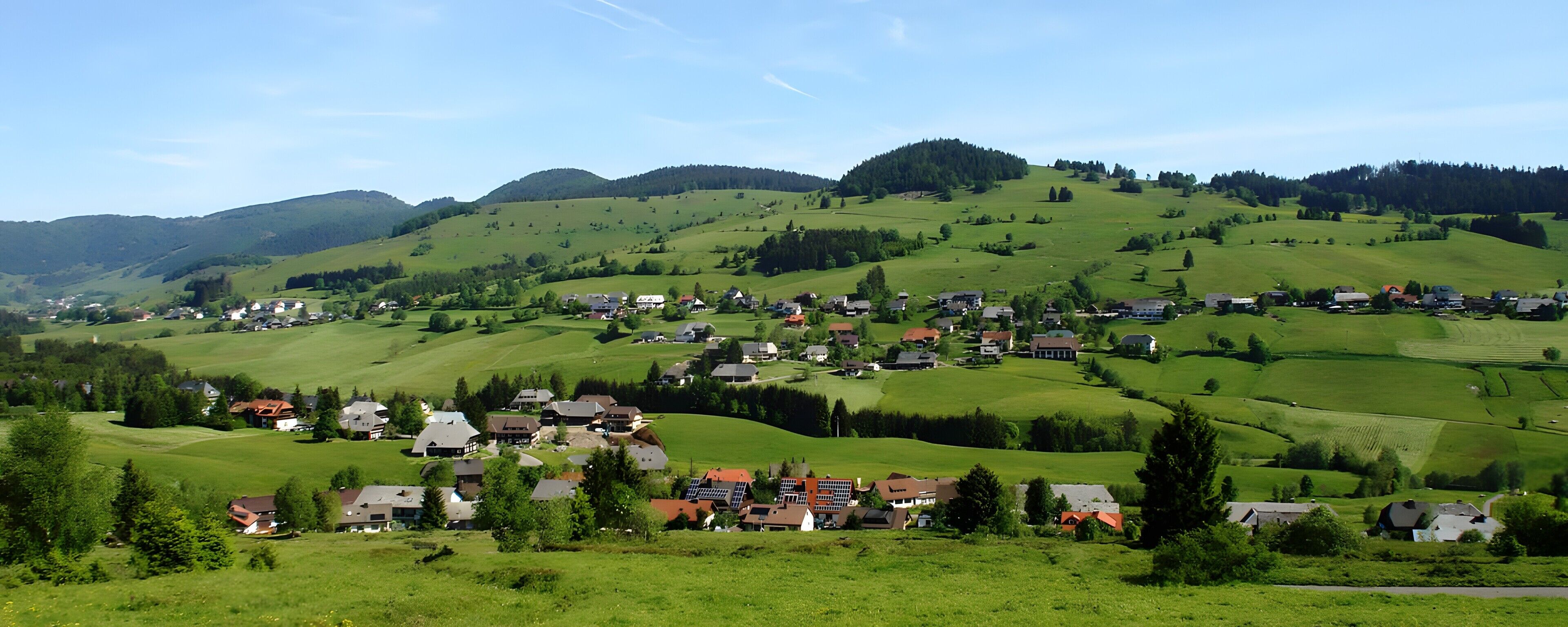 A rural village with houses spread across rolling green hills.