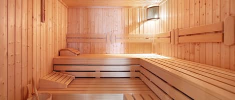 Un sauna avec des bancs en bois et une banquette, des murs en bois et un thermomètre fixé au mur.