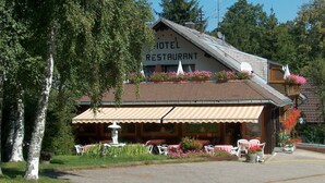 A hotel with a restaurant, outdoor seating, and a fountain. - Hotel Bären – Drei Sterne: Doppelzimmer 8 inkl. Frühstück, Balkon, Bergblick, WLAN (Bernau im Schwarzwald)