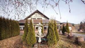 A hotel with a sign reading 'HOTEL RESTAURANT,' surrounded by neatly trimmed hedges and a stone fountain. - Hotel Bären – Drei Sterne: Doppelzimmer 8 inkl. Frühstück, Balkon, Bergblick, WLAN (Bernau im Schwarzwald)