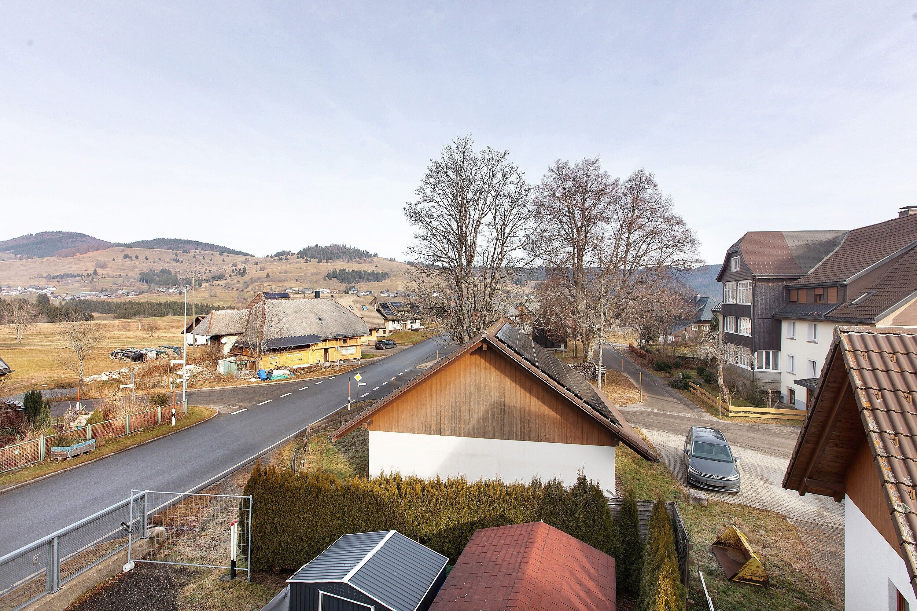 A residential area with houses, a road, and a hilly landscape in the background.