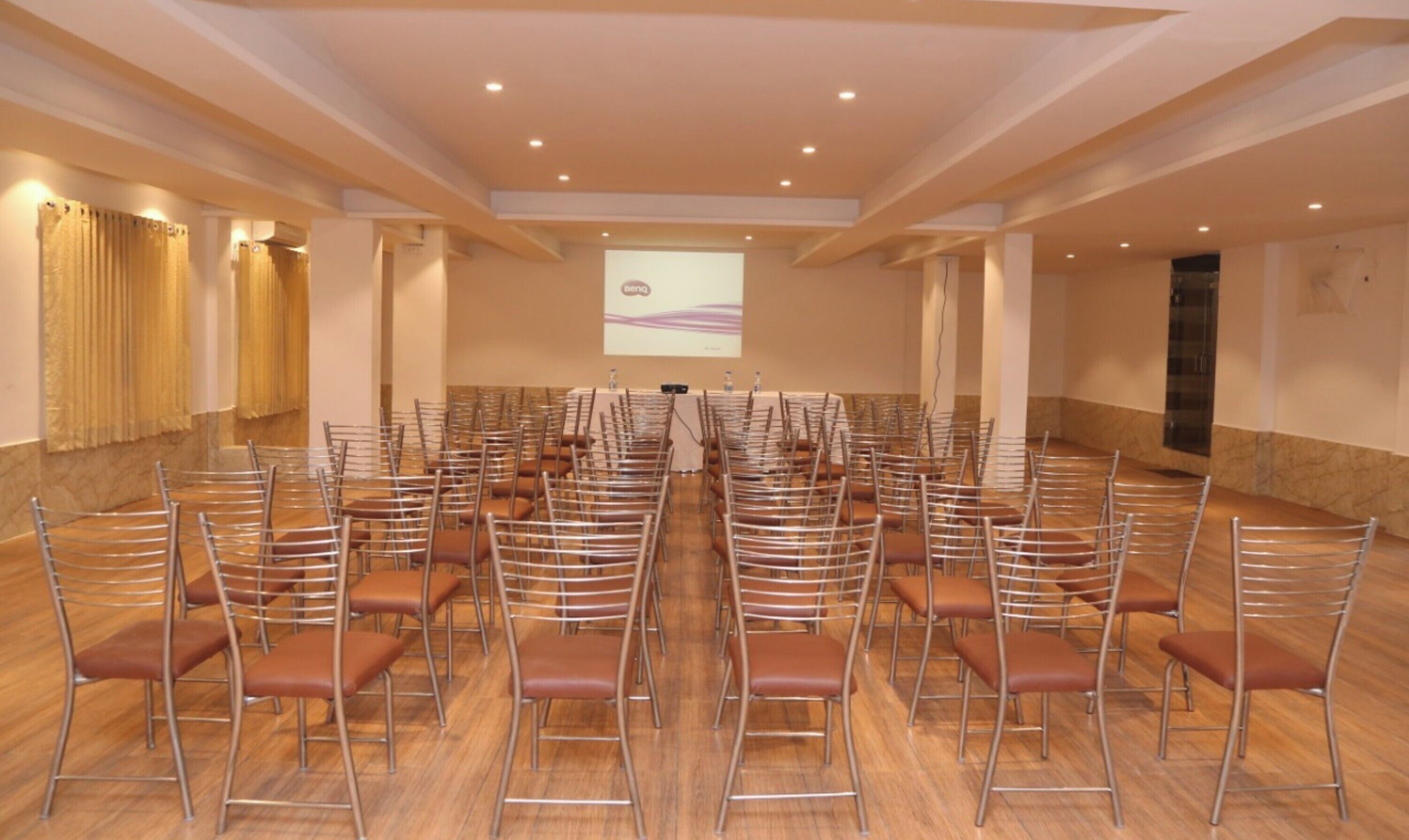 A conference room with rows of chairs, a podium, and a projection screen.