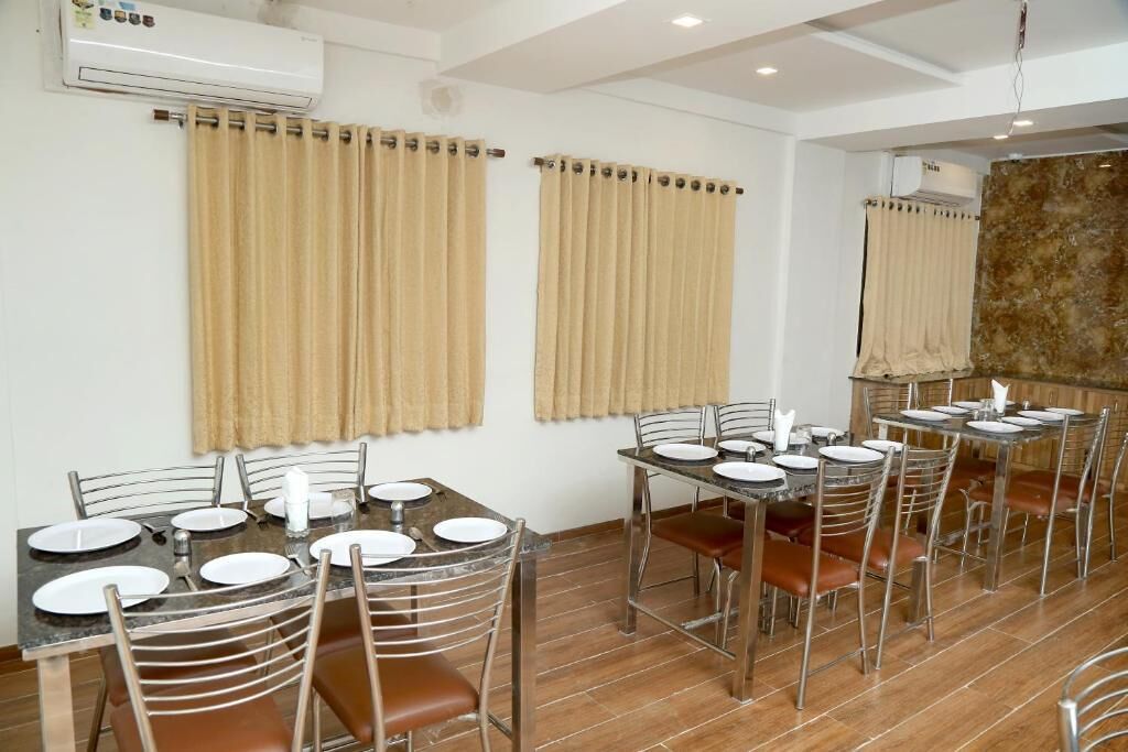Un espace repas comprenant plusieurs tables et chaises, des unités de climatisation et des rideaux de couleur beige.