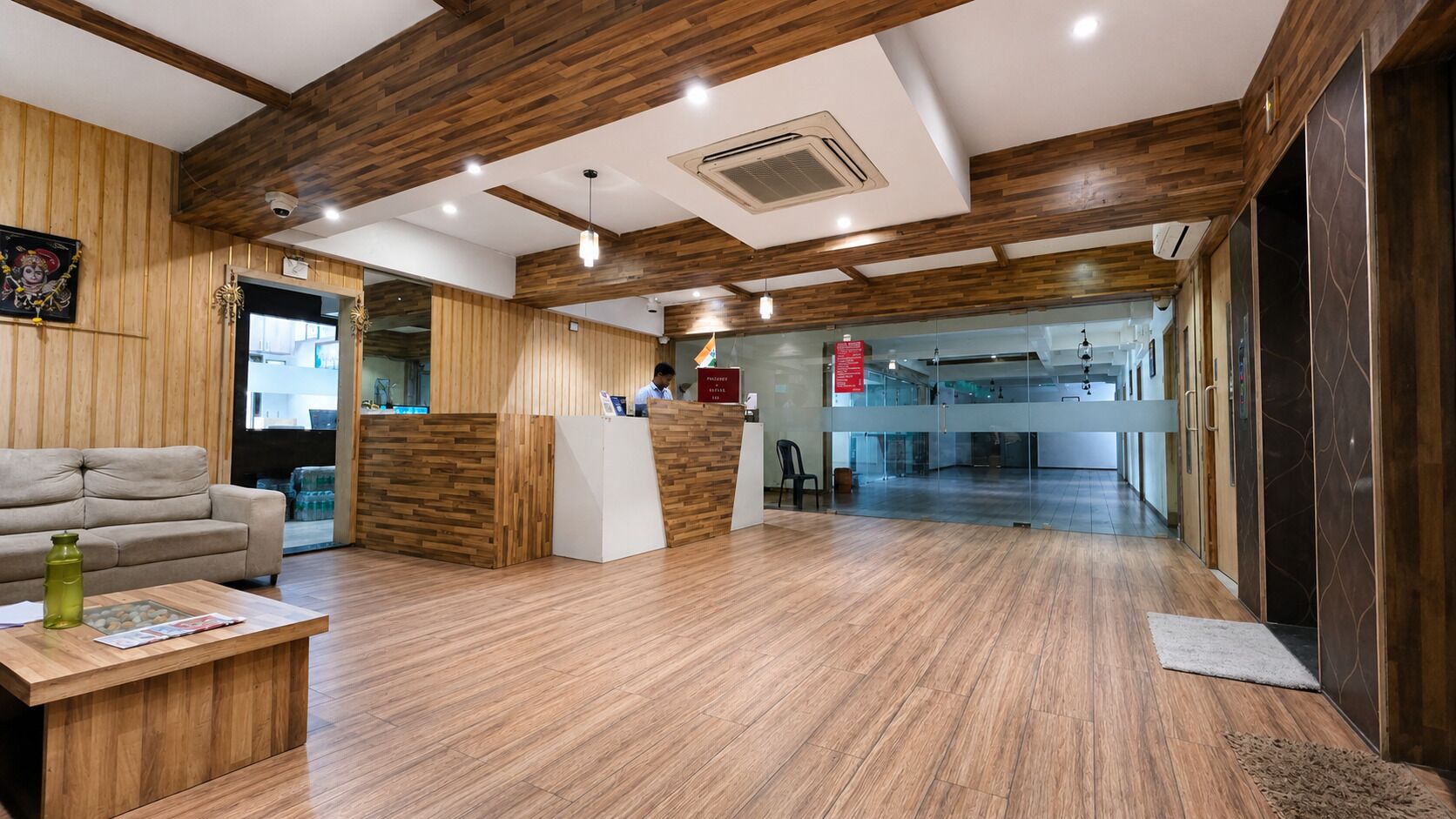 A reception area with a wooden reception desk, a sofa, a coffee table, and a glass partition.