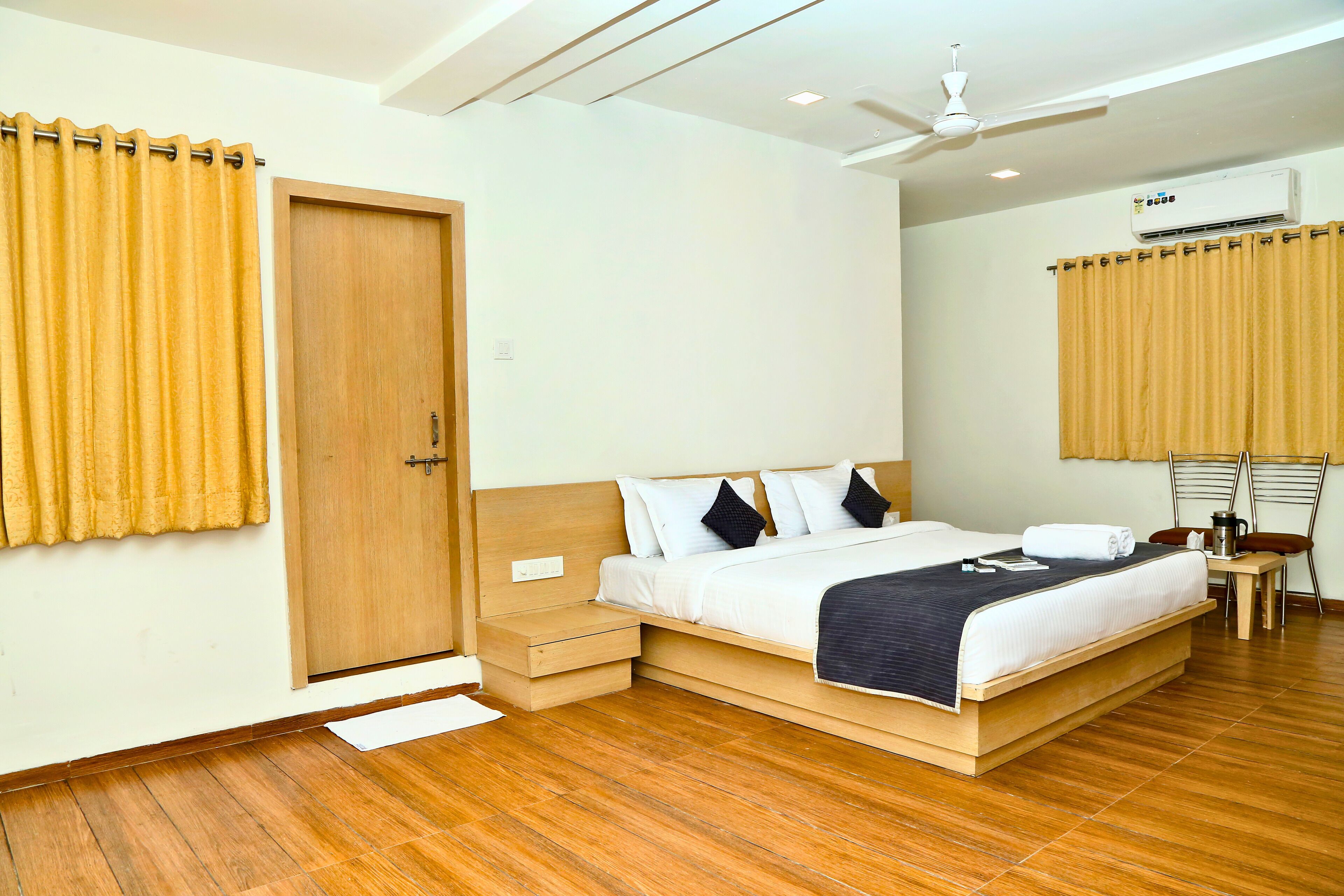 Une chambre à coucher avec un lit en bois, une table de chevet, un ventilateur de plafond et un appareil de climatisation.