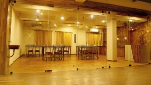 Una sala conferenze con pareti in vetro, pavimento in legno e un tavolo con sedie.