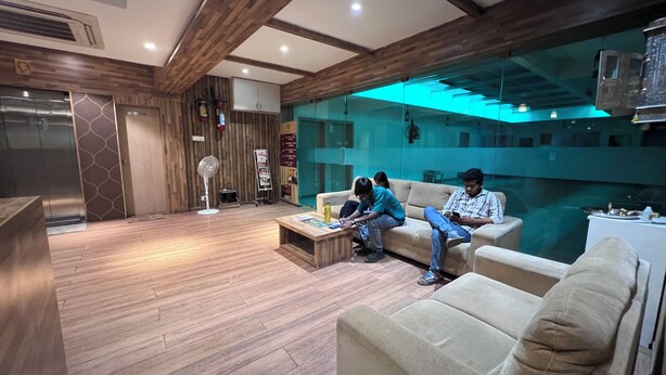 Un interno moderno con pavimento in legno, una parete divisoria in vetro e un'area salotto con un divano e un tavolo.
