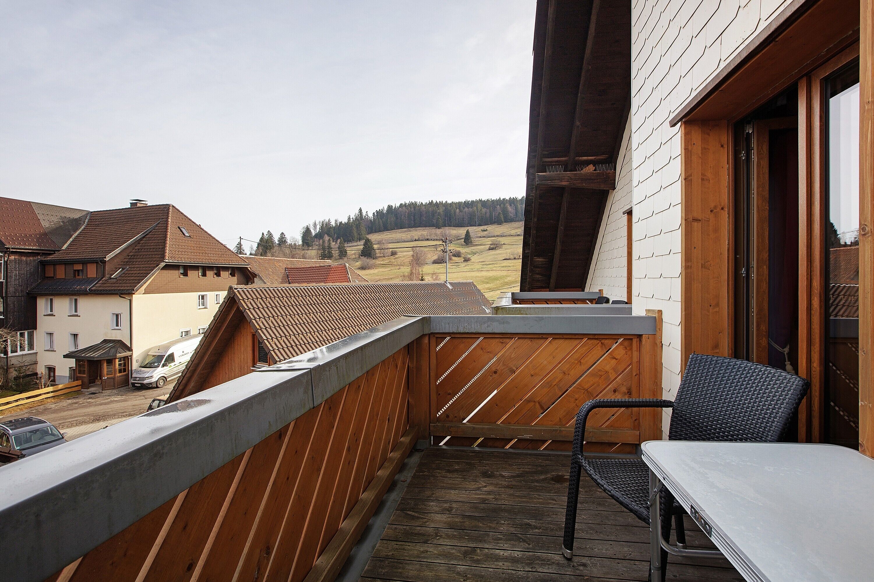 Un balcon donnant sur un paysage vallonné, avec une table et une chaise.