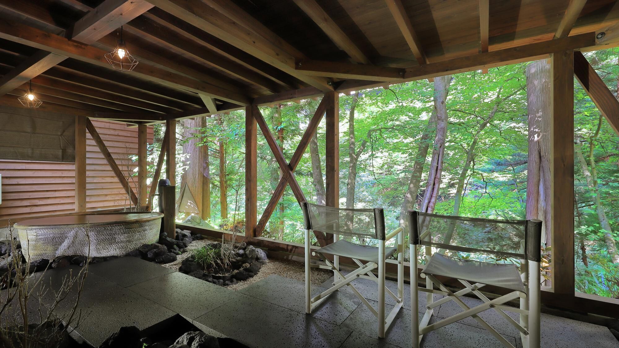 Un espace extérieur aménagé, abrité et doté de sièges, offrant une vue sur une forêt.