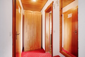 Un pasillo con puertas de madera y una alfombra roja.