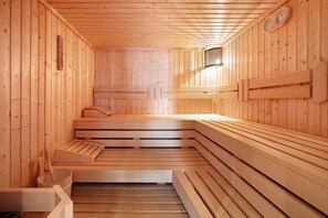 A sauna with wooden benches and a bench seat, wooden walls, and a wall-mounted thermometer. - Hotel Bären - Three-Star: Double Room 10 / Breakfast Included / 2 Guests / Mountain View / WiFi (Bernau im Schwarzwald)