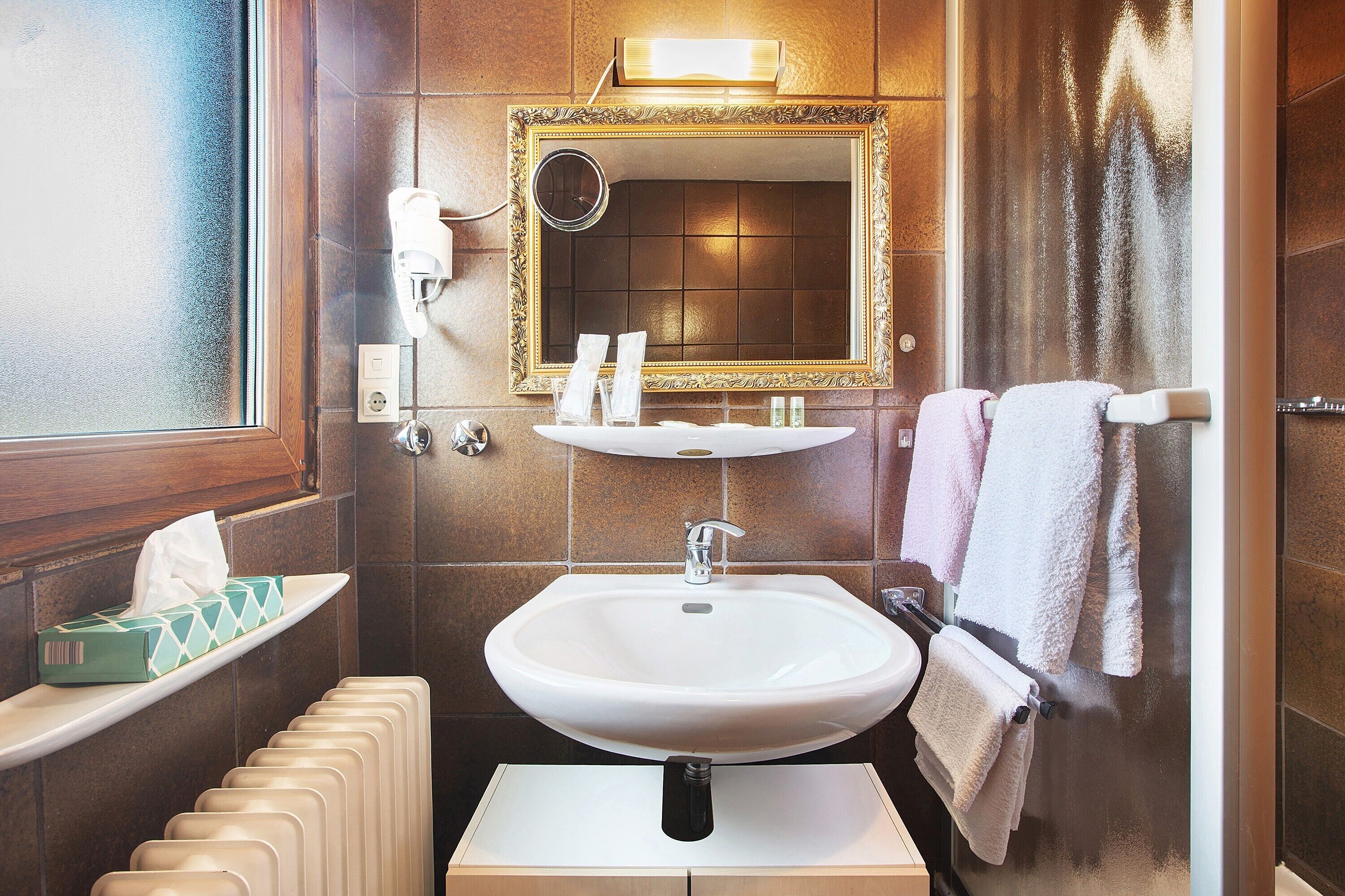 A bathroom with a sink, mirror, towel rack, and a tissue box on a shelf.