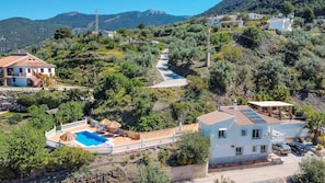 Une propriété située sur une colline, dotée d’une piscine, d’un patio couvert et offrant une vue sur le paysage environnant.