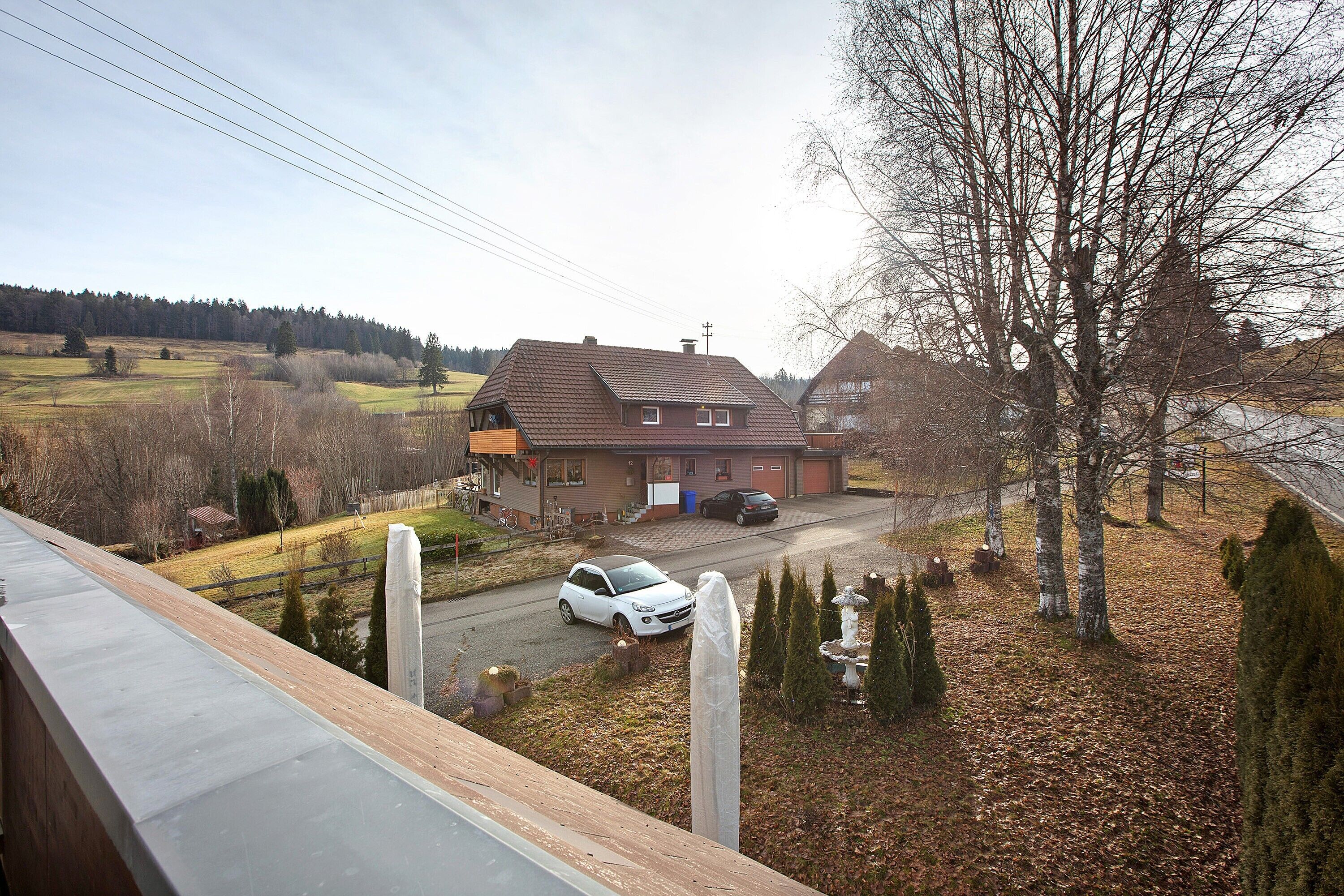 Une maison d’habitation avec une allée, une voiture garée et une vue dégagée sur le paysage environnant.
