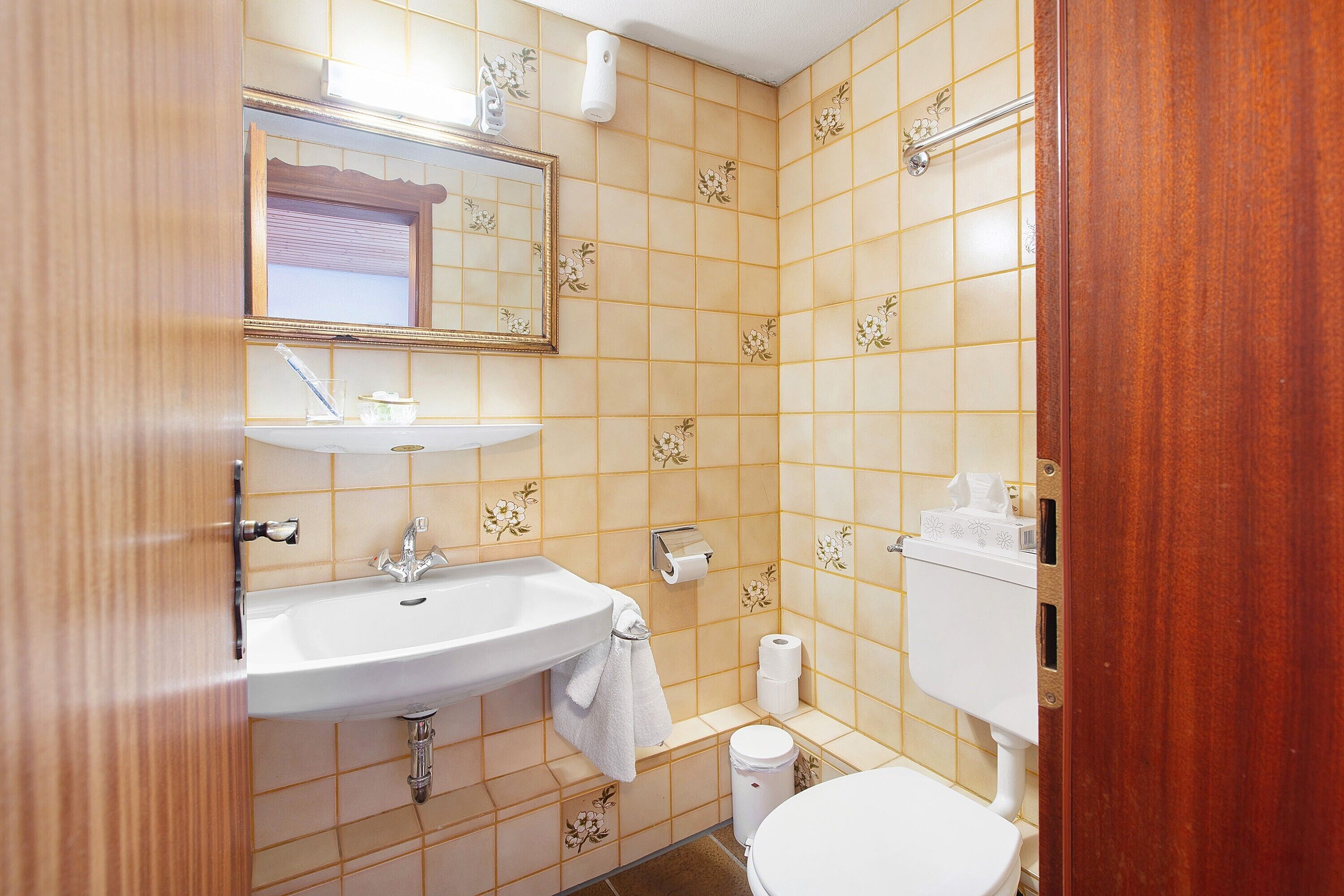 Een badkamer met een wastafel, spiegel, toilet en een handdoek aan de muur.