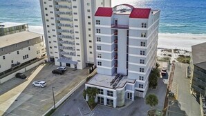 Un hôtel à plusieurs étages, avec un toit rouge, situé près d’une plage.