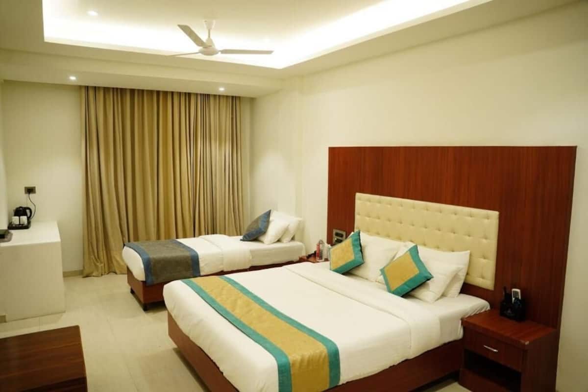 A hotel room with two beds, a ceiling fan, a desk, and a minibar.