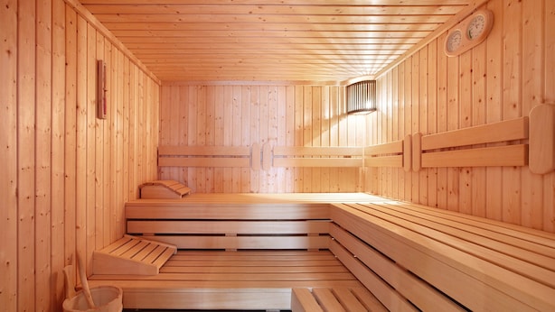 En sauna med træbænke og en bænk, trævægge og et termometer på væggen.