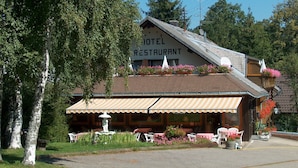 Et hotel med restaurant, udendørs siddepladser og en springvand.