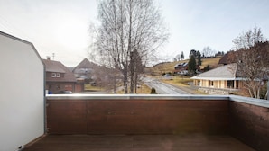 En balkon med udsigt over en boligvej og huse.