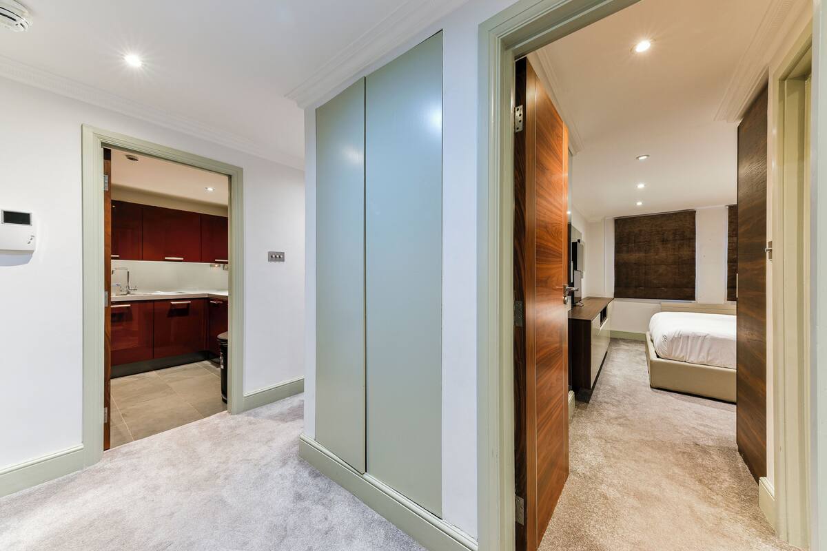 Ein Hotelzimmer mit großem Schrank, einem Bett und einem Badezimmer mit Spiegel und Waschbecken.