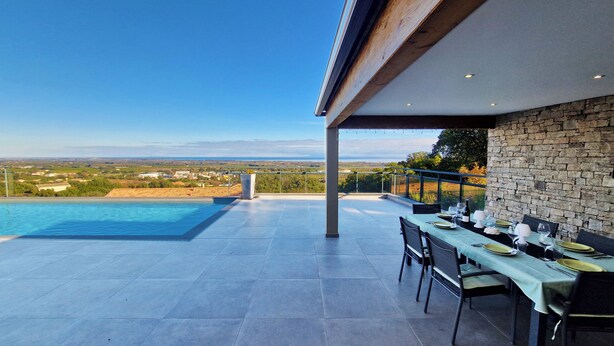 A rooftop pool area with a dining setup overlooking a scenic landscape. - Villa de prestige en Haute-Corse - Sea view & exceptional amenities (Penta-di-Casinca)