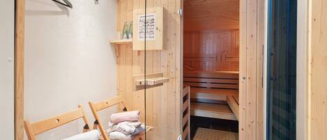 A wooden sauna room with benches, towels, and a glass door.
