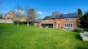 A two-story brick house with a large front lawn and a garage. - Riverside Cottage (Marlborough)