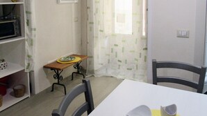Ein Essbereich mit Tisch, Stühlen, einem kleinen Beistelltisch mit Teller und einer Wanduhr.