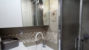 Ein modernes Badezimmer mit einem weißen Waschbecken, einem Spiegel und einem Edelstahl-Kühlschrank.