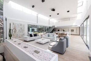 A spacious living area with a modern white sofa set, a coffee table, and a large window overlooking a garden. - Modern Villa Biot, Entire home in Biot, France (Biot)