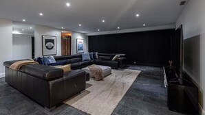 A modern living room with a sectional sofa, a flat-screen TV, and a dark curtain backdrop. - Modern Villa Biot, Entire home in Biot, France (Biot)