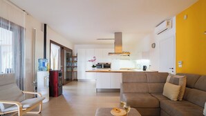 A modern living room with a sofa, a coffee table with two pastries and glasses, a kitchen with a central island, and a sliding glass door leading to a balcony. - Beautiful private villa for 12 guests with WIFI, private pool, A/C and TV, close to Ostuni (San Vito Dei Normanni)