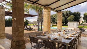 An outdoor dining area with a long table set for a meal, surrounded by stone pillars and a covered patio. - Beautiful private villa for 12 guests with WIFI, private pool, A/C and TV, close to Ostuni (San Vito Dei Normanni)