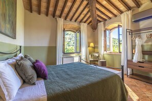Ein Schlafzimmer mit einem Bett, einem Sessel, einer Lampe und einer Holzkommode.