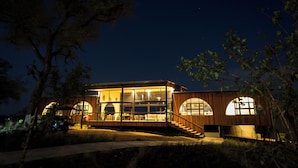 Una casa moderna con ampie vetrate, rivestimento in legno e una scala che conduce all'ingresso.
