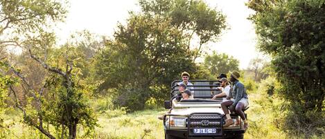 A vehicle with four passengers on a dirt road surrounded by trees.
