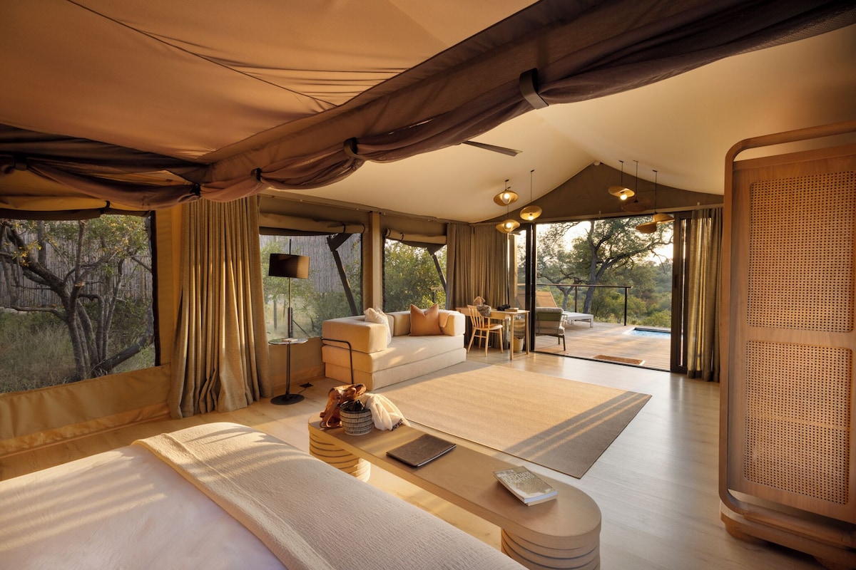 A spacious room with a large bed, a sofa, a dining area, and a view of the outdoors.