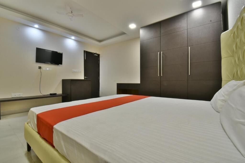 A hotel room with a bed, a wardrobe, a television, and a desk.