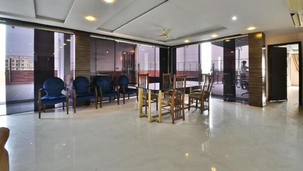 A spacious room with a high ceiling, large windows, and a modern interior design. - THE CLOVERS INN (Patna)
