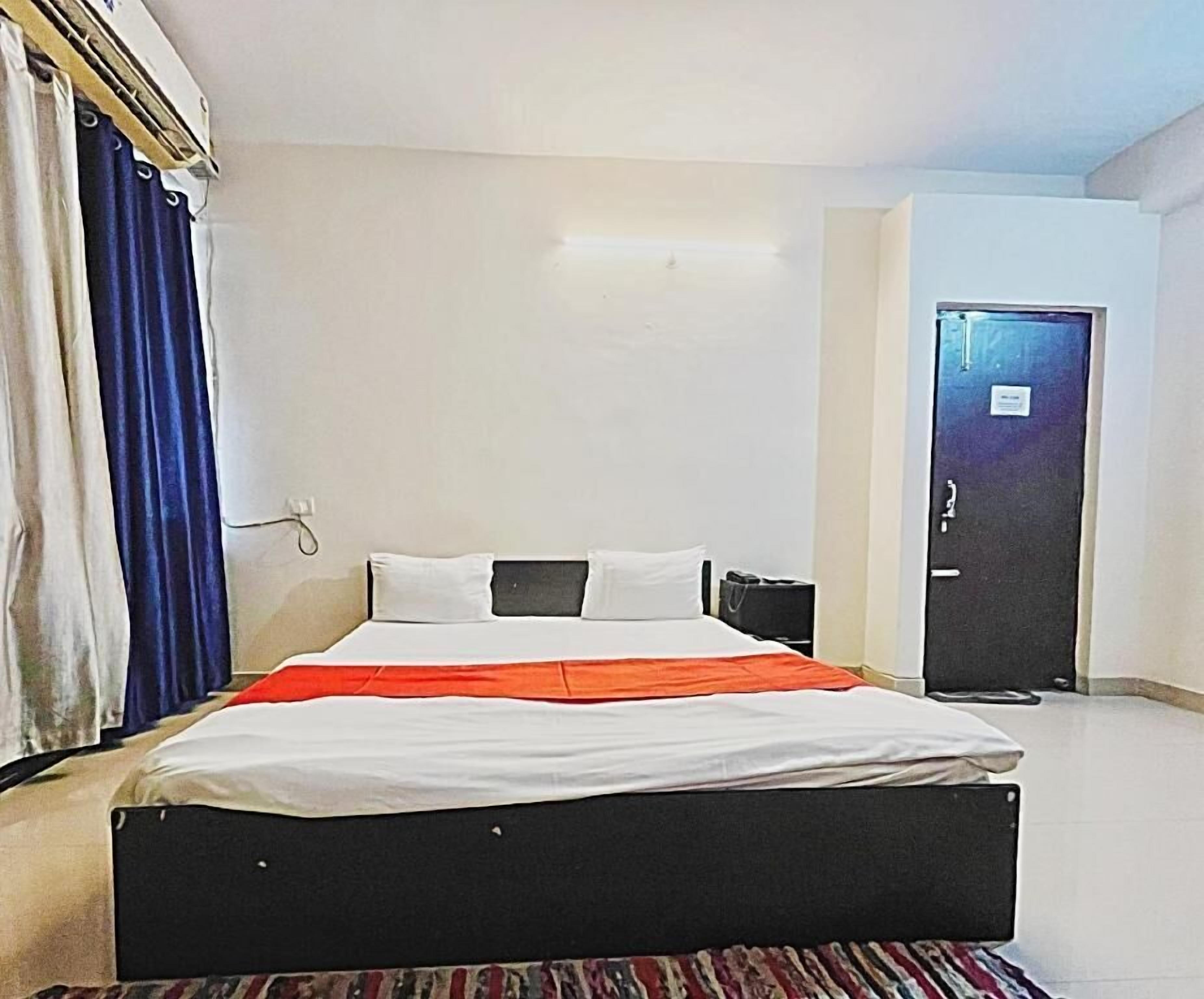 Una habitación de hotel con cama, puerta y cortina.