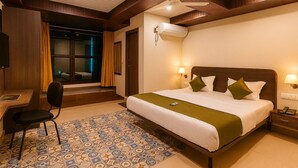 A hotel room with a large bed, a desk, and a chair. - THE CLOVERS INN (Patna)