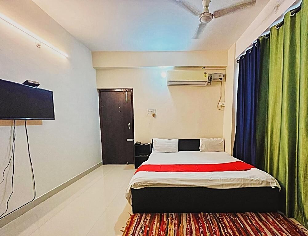 Una camera d'albergo con un letto, una televisione a schermo piatto, un condizionatore d'aria e una ventola a soffitto.