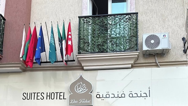 A hotel entrance with a sign reading "SUITES HOTEL Dar Farhat" and multiple flags displayed outside. - Hotel dar farhat (Tunis)