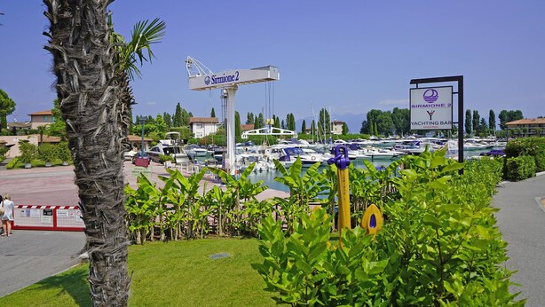 En småbåtshamn med båtar, en kran och en skylt för Sirmione 2 Yacht Club.
