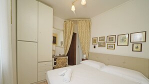 Ett hotellrum med en säng, ett skrivbord, en stol, en garderob och en duschhörna.