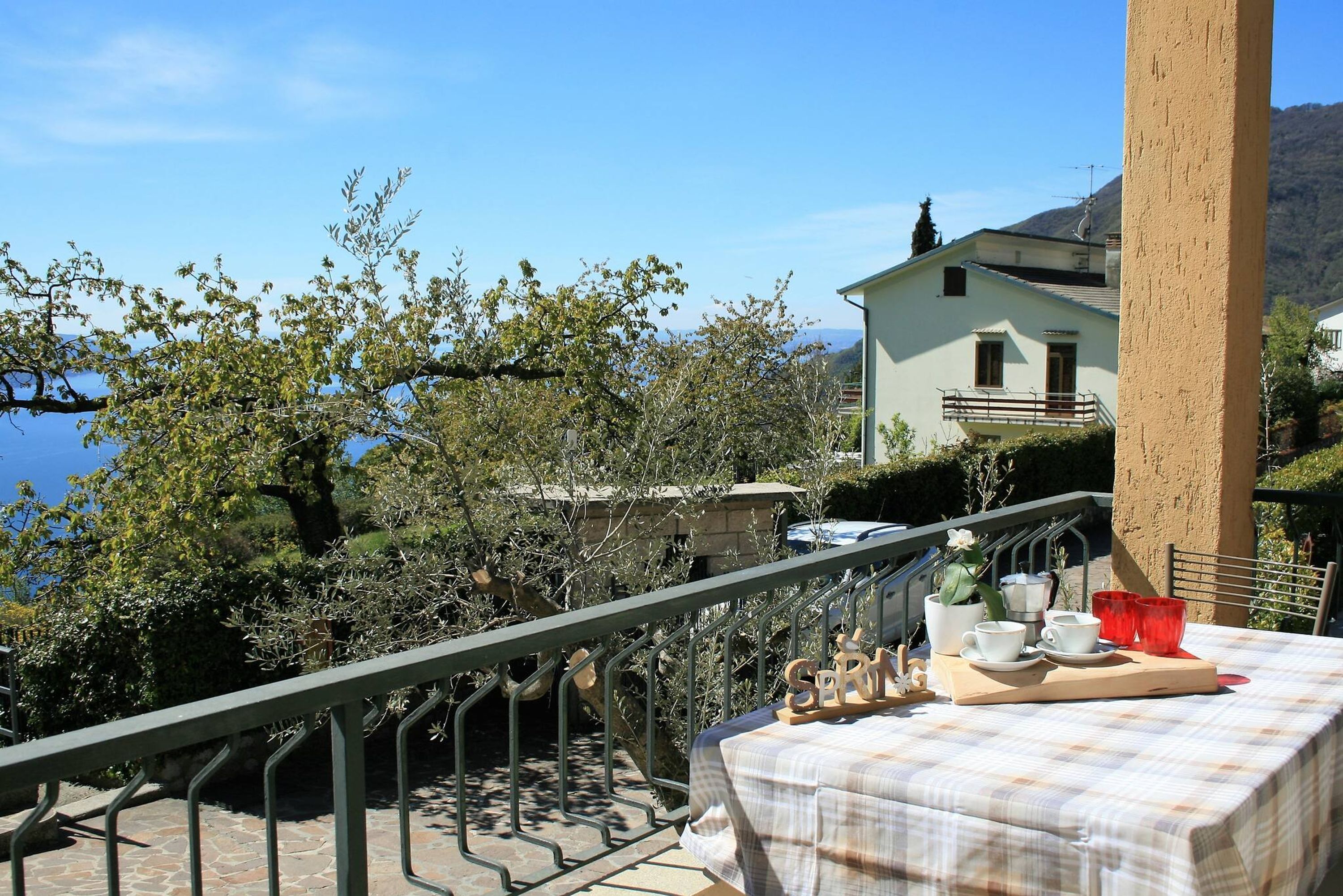 Eine Terrasse mit Tee-Apotheke, Blick auf einen See und einen Berg.